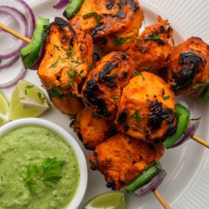 Indian chicken tikka kebabs, marinated in spices and yogurt and roasted in tandoor. served with green chutney and onion. selective focus